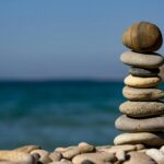 A stack of balanced stones on a beach with a tranquil ocean backdrop for meditation and zen.