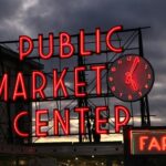 Neon sign of Pike Place Market in Seattle at sunset, highlighting the famous landmark.